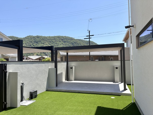 赤穂市新築外構庭にあるテラス タカショーのホームヤードルーフⅡシングル仕様屋根直線色はマットブラックポリカはクリアマット 内天井屋根シングル仕様色はくり柾目。タイルデッキはオオムラエコストーン色はグレーの様子